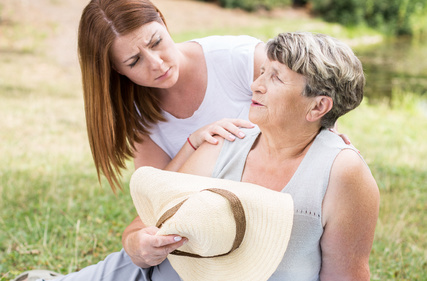 middle aged daughter looking at her older mother in concern as she sits on the ground