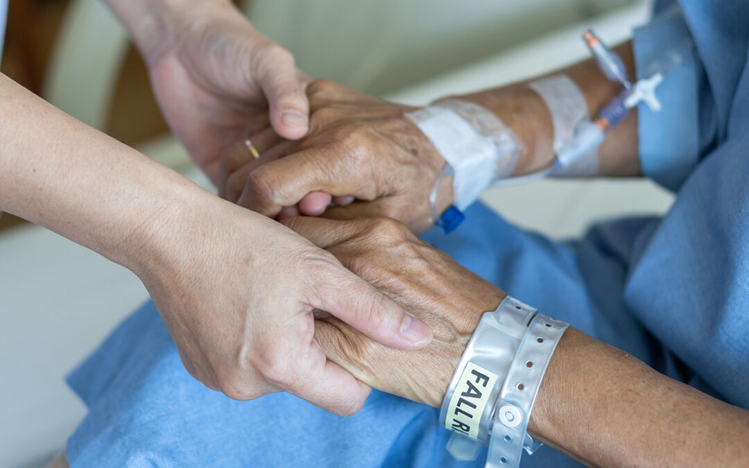 Elderly patient on bed with geriatric nurse holding hands
